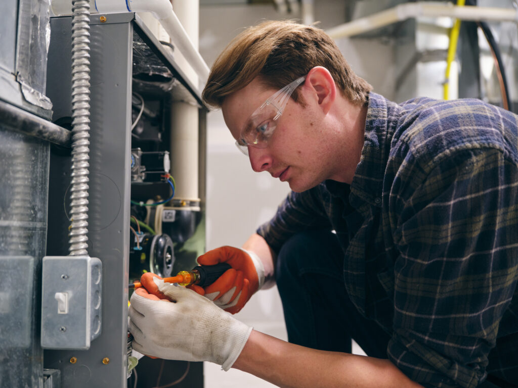 HVAC technician performing furnace services on residential heating unit